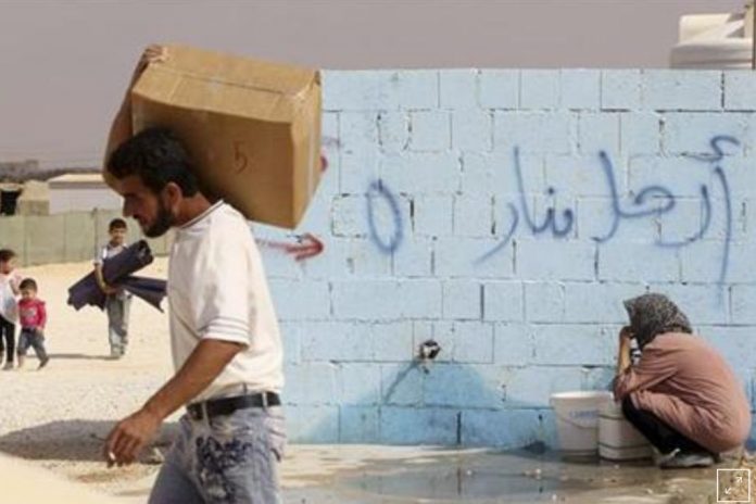 A Syrian refugee collects water at the Al Zaatri refugee camp. A Syrian refugee collects water at the Al Zaatri refugee camp.