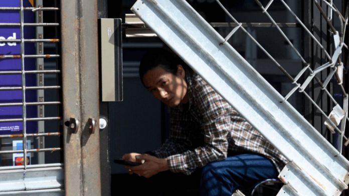 Employee looks trough the broken gate at a phone store Employee looks trough the broken gate at a phone store