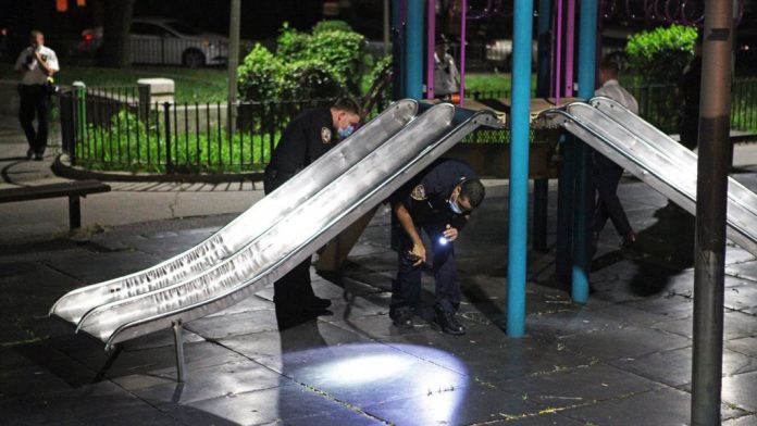 Police Officers investigate at the scene of a shooting in Brooklyn.