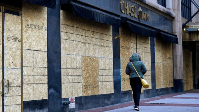 A woman walks past boarded-up businesses on the eve of the 2020 General Election A woman walks past boarded-up businesses on the eve of the 2020 General Election