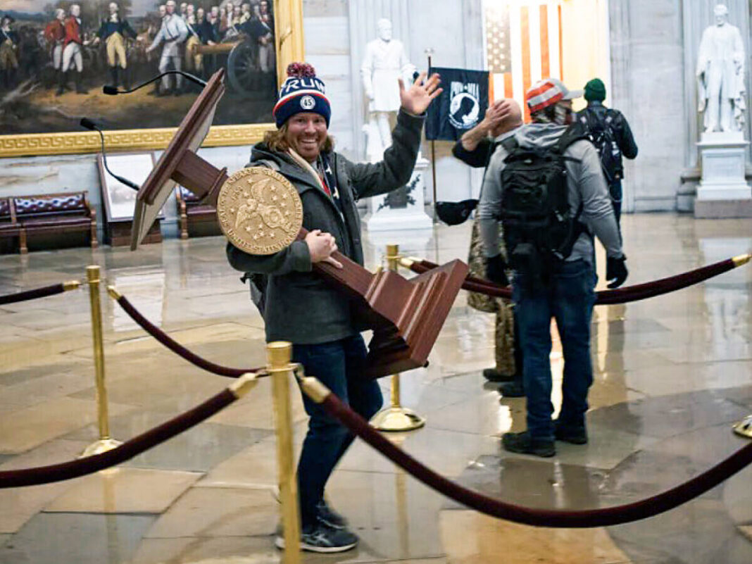 Adam C. Johnson totes House Speaker Nancy Pelosi's podium at the U.S. Capitol on Jan. 6, 2021.