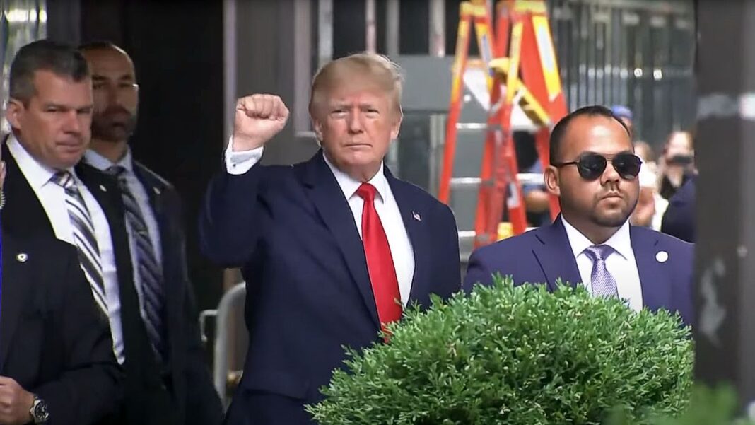 Former President Donald Trump raises his fist while walking to a vehicle