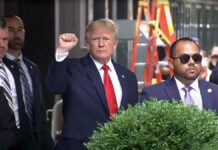 Former President Donald Trump raises his fist while walking to a vehicle