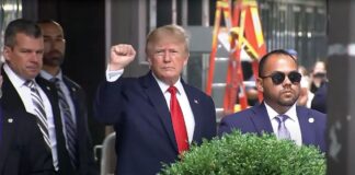 Former President Donald Trump raises his fist while walking to a vehicle