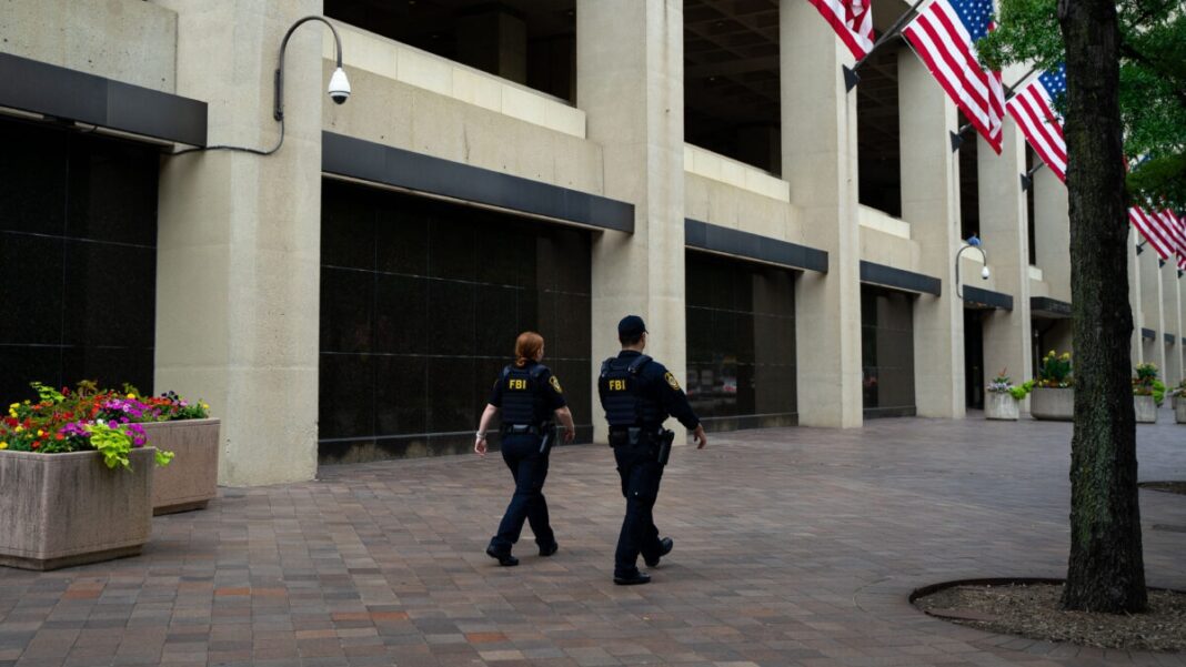 Law enforcement officers walk past the J. Edgar Hoover FBI Building