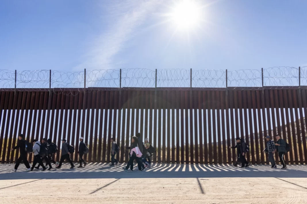 Illegal immigrants who passed through a gap in the U.S. border wall await processing by Border Patrol agents in Jacumba, Calif., on Dec. 7, 2023. (John Fredricks/The Epoch Times)