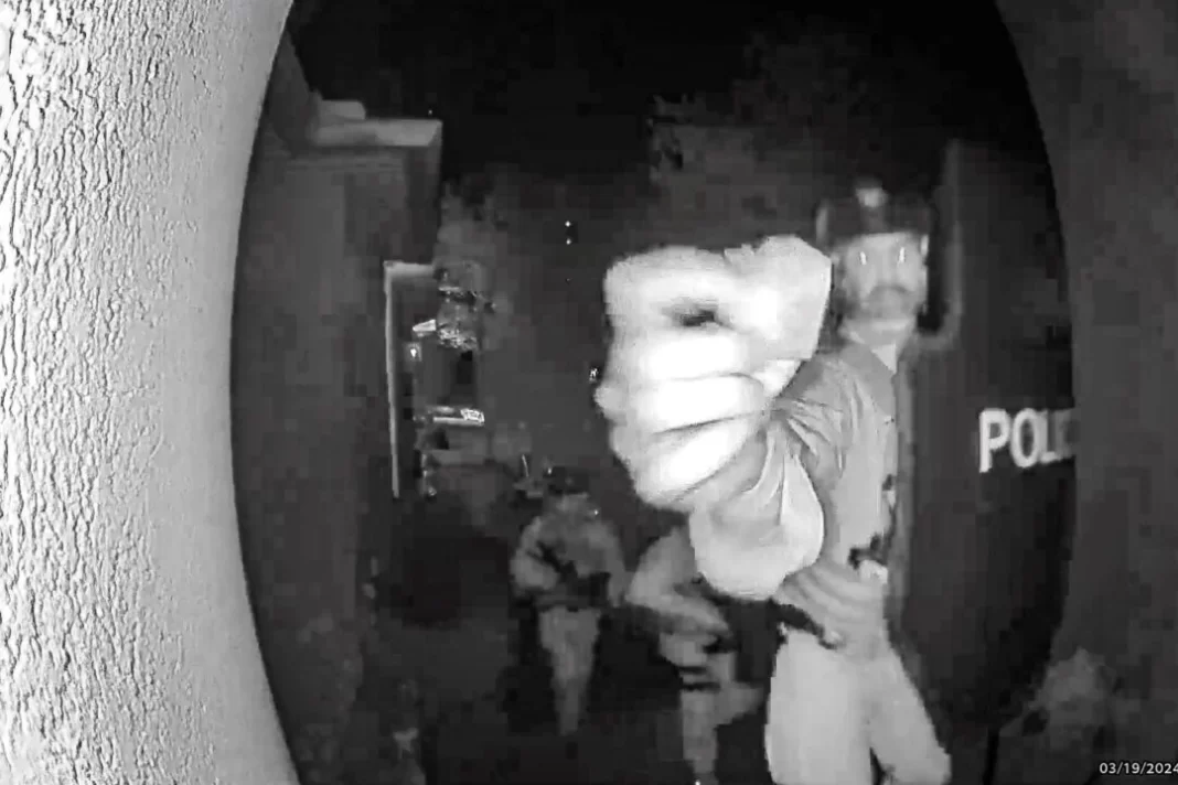 An armed ATF agent reaches toward the doorbell camera at the home of Bryan Malinowski.