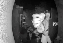 An armed ATF agent reaches toward the doorbell camera at the home of Bryan Malinowski.