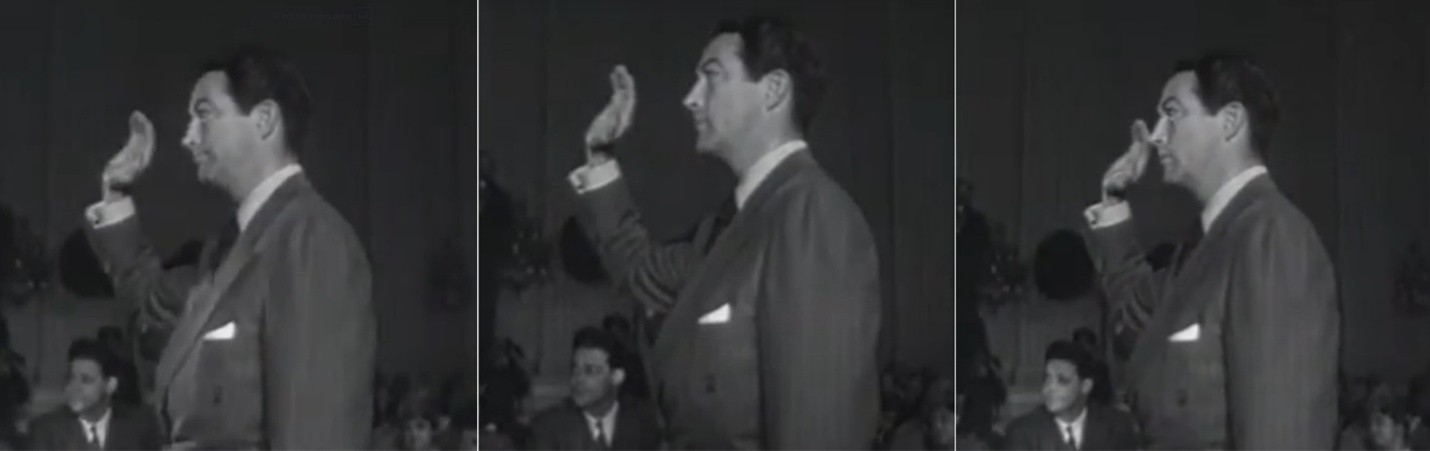 Robert Taylor raising his hand to take the oath. He was rebuked because photographers couldn’t see his face. Taylor reacts, grimacing, and pulls his hand back to comply.