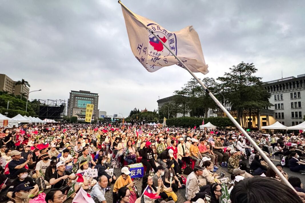 People wave flags and cheer at a “Reject United Front, Defend Taiwan” rally in Taipei, Taiwan, on April 19, 2025.
